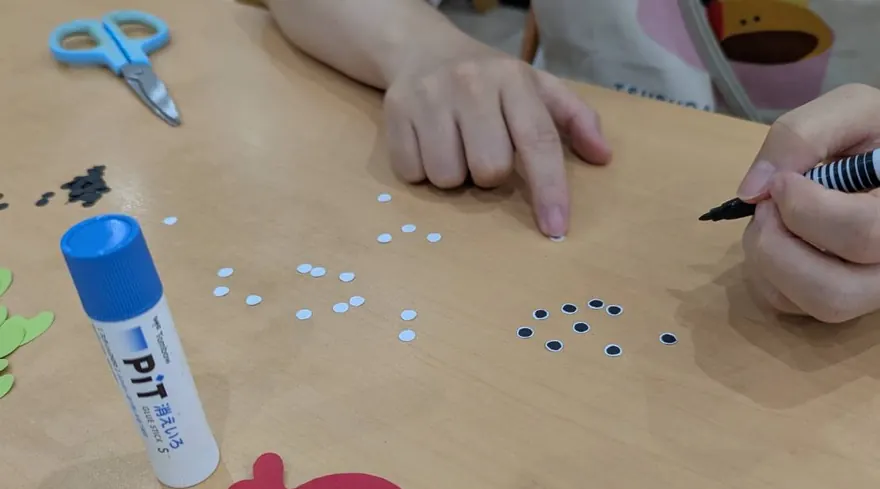 机の上にのりやはさみ、紙の丸シールを広げて制作活動をしているところ